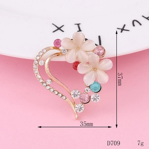 Detail view of heart-shaped gold alloy brooch with opal flowers and rhinestones