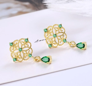 Detail showing vintage gold hollow flower earrings with emerald green teardrop tassels