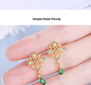 Close-up of Chinese style gold filigree earrings with emerald green teardrop pendants