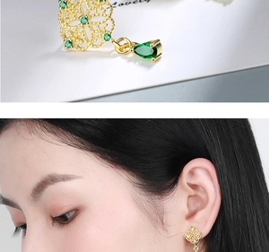 Detail of gold hollow earrings with green emerald stones and teardrop fringe pendants
