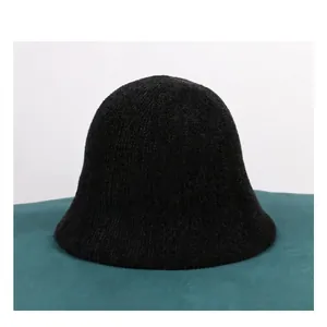 Detailed view of black knitted chenille bucket hat texture on a green soft surface