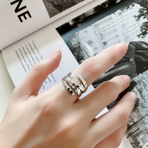 Detail of multi-layer woven silver metal ring worn against a fashion magazine backdrop