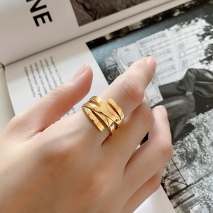 Detailed close-up of a golden woven layered ring worn by a model against a magazine backdrop