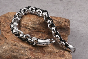 Detail of men's punk leather bracelet with silver and black metal clasp on brown rock