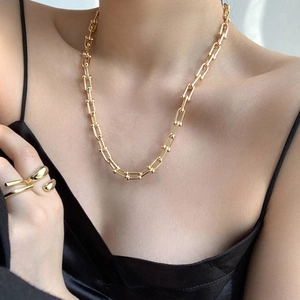 Macro detail of industrial style gold-plated necklace and ring set on model
