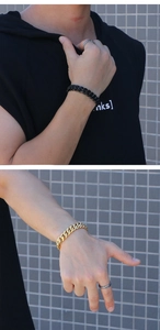 Détail de bracelets gourmette noir mat et or portés avec une bague en argent vintage