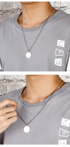 Primo piano di una modella che indossa una semplice collana con ciondolo tondo argento