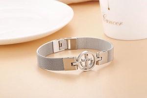 Détail macro du bracelet en maille d'acier argenté avec breloque ancre et cristaux