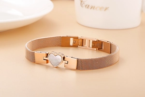 Detail of rose gold mesh strap bracelet with a white heart-shaped shell inlay