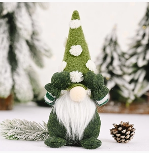 Detailed view of a green faceless Christmas gnome with white polka dots covering its eyes