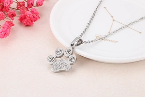 Macro view of silver animal paw pendant featuring sparkling crystals on a ceramic tray