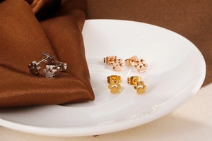 Détails de boucles d'oreilles patte d'animal en argent, or rose et or sur assiette blanche