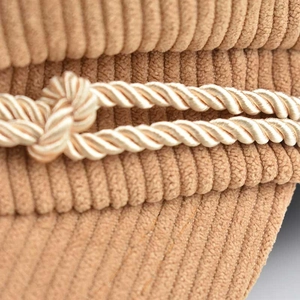 Detailed macro view of khaki corduroy texture and braided rope trim on octagonal cap