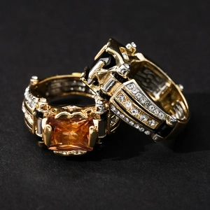 Macro shot of two retro style gold rings with orange and black stones on black texture