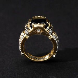 Macro view of a gold-plated ring with a square black gemstone and pavé-set side stones