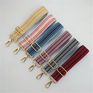 Close-up of adjustable woven purse straps with geometric patterns and gold buckles