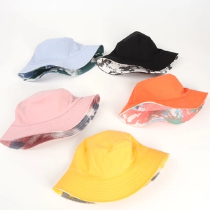 Flat lay of reversible cotton bucket hats showing solid colors and tie-dye inner linings