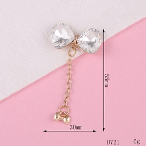 Detailed view of metal bow charm with crystal stones and tassel, 55mm long, model D721
