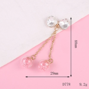 Detail view of bowknot pendant with pink glitter glass balls and metal chains