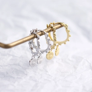 Detailed macro view of S925 sterling silver sunburst pendant hoop earrings in gold and silver