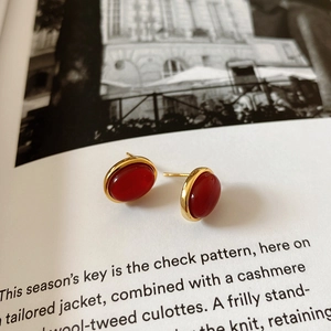 Detailed view of red oval agate studs with gold bezel on a fashion magazine background