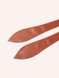 Detail of terracotta leather waist belt showing spade end tip and fine tonal stitching
