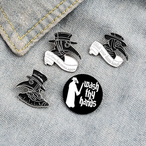 Set of four plague doctor enamel pins in black and white on blue denim fabric