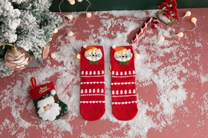 Close-up of red cotton Christmas socks with cute cartoon cat patch and festive patterns