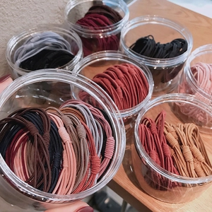 Set elastici per capelli in colori assortiti e barattoli trasparenti su tavolo in legno