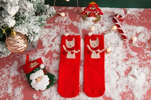Close-up of red Christmas cotton socks featuring cute pets and festive holiday decor