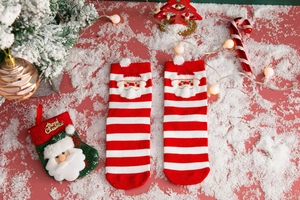 Close-up of red and white striped Christmas socks with 3D Santa Claus on faux snow