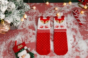 Detail of red Christmas socks with knitted cartoon reindeer patterns and festive textures