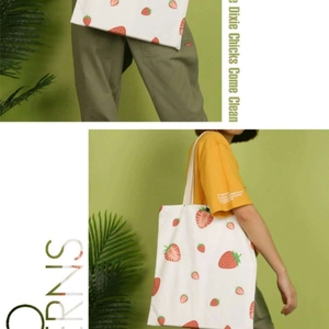Close-up of white canvas tote bag featuring vibrant red strawberry floral print patterns