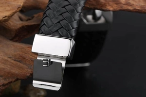 Close-up of black braided leather texture and silver stainless steel buckle of men's bracelet