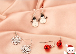 Close-up of Christmas earrings featuring white snowmen, snowflakes and red festive bells