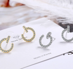 Close-up of gold and silver minimalist stud earrings with small crystals on a card