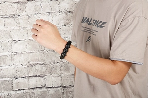 Close-up of a men's punk bracelet featuring black matte skull charms on a wrist