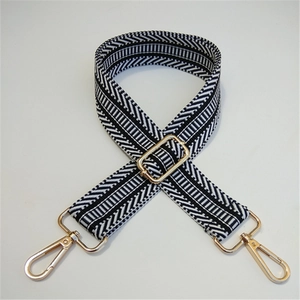 Detail of adjustable embroidered bag strap with black white chevron pattern and gold clips