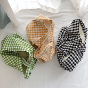 Flat lay detail of plaid cotton tote bags in green, orange, and black checkered patterns