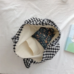 Macro view of checkered cotton tote bag showing inner pocket and floral pouch storage