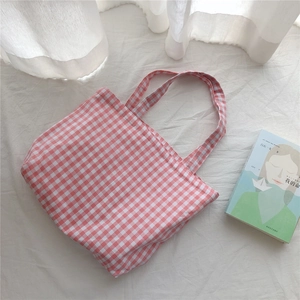 Detail of red and white checkered canvas tote bag on soft white fabric background