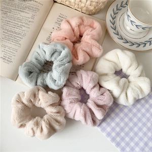 Detailed view of five plush faux fur hair scrunchies in soft macaron pastel colors