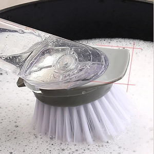 Long-handle kitchen dish brush with gray head and white bristles in soapy water scene