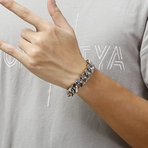Close-up of a chunky silver stainless steel Cuban link bracelet worn on a man's wrist