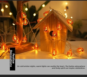 Close-up of Halloween pumpkin LED string lights with warm yellow glow on a wood stand