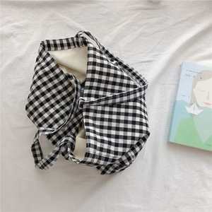 Detailed top view of a black and white checkerboard canvas tote bag on white fabric