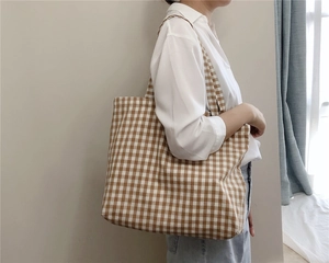 Brown and white gingham canvas tote bag worn by a model in a minimalist lifestyle setting