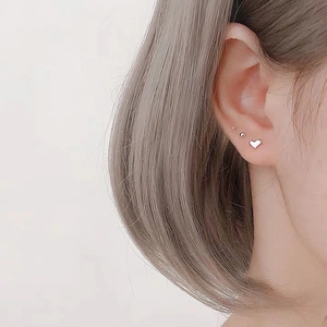 Elegant heart-shaped silver stud earrings shown on model for a minimalist fashion look