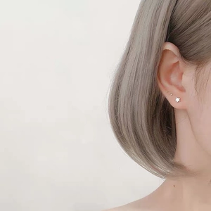 Close-up of minimalist S999 sterling silver star stud earring worn by a model