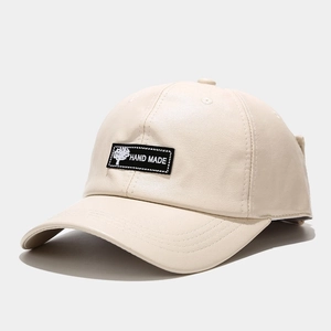 Close-up of beige PU leather baseball cap featuring handmade logo and litchi texture